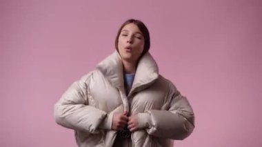 Pembe arka planda kurnaz yüz ifadesi olan bir kızın 4K videosu. Fikirleri olan kız kavramı.