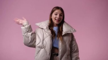 Pembe arka planda hoş bir kızın el salladığı 4K video. Duyguların kavramı.