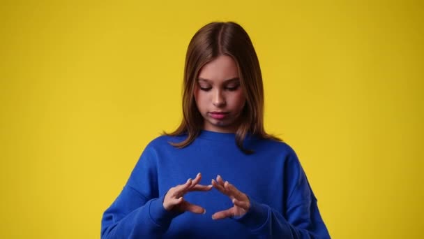 4Kビデオの女の子作る心の形に彼女の手で黄色の背景 愛の感情の概念 — ストック動画