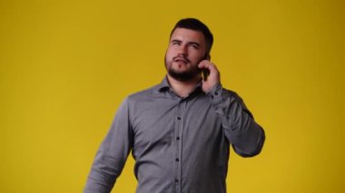 Sarı arka planda telefonu kullanan bir adamın 4K videosu. Duyguların kavramı.