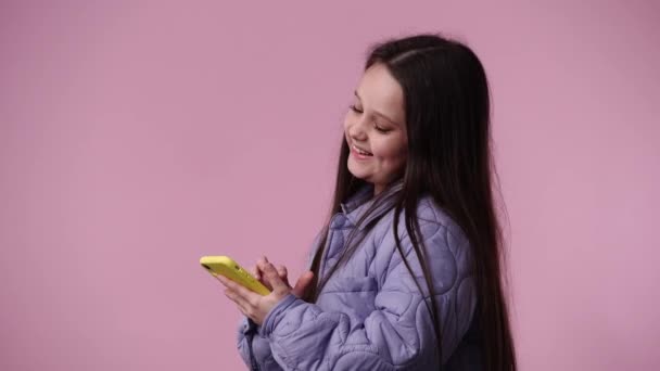 ピンクの背景にテキストを入力する1人の女の子の4Kビデオ 感情の概念 — ストック動画