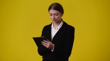 4k video of one girl taking notes over yellow background. Concept of emotions.