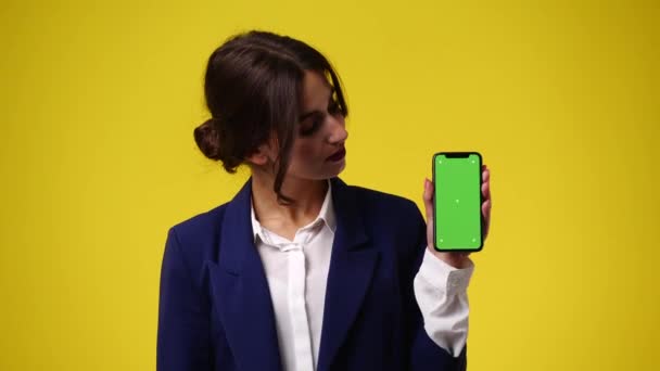 クロマキー電話で一人の女の子の4Kビデオや黄色の背景に親指を下に表示します 感情の概念 — ストック動画
