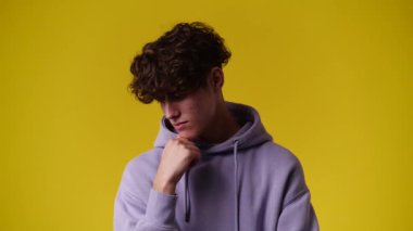 Sarı arka planda düşünceli yüz ifadesi olan bir adamın 4K videosu. Fikirleri olan insan kavramı.