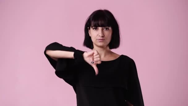 ピンクの背景に親指を示す1人の少女の4Kビデオ 負の感情の概念 — ストック動画