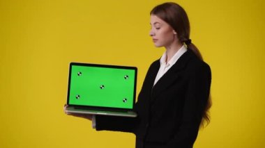 Krom anahtar dizüstü bilgisayar kullanan bir kızın 4k videosu ve sarı arkaplan üzerinde başparmak göstermesi. Duygu anlayışı..