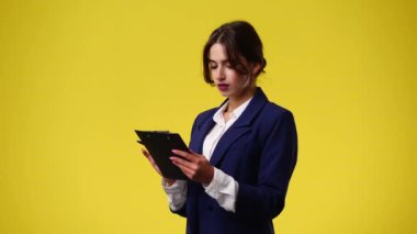 4k video of one girl taking notes over yellow background. Concept of emotions.