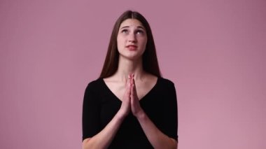 4k video of one girl crosses his fingers and believes in something over pink background. Concept of emotions.