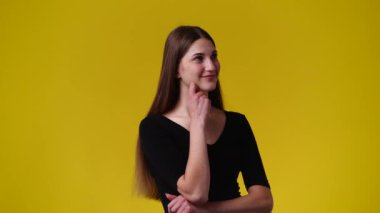 Bir kızın poz verdiği ve sarı arka planda bir şeyin hayalini kurduğu 4k yavaş çekim videosu. Duyguların kavramı.