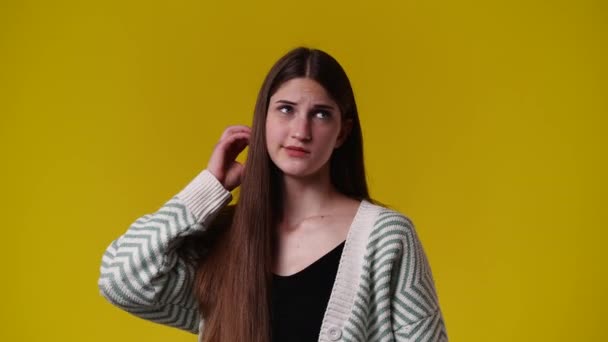 彼女の髪に触れる1人の女の子の4Kビデオと黄色の背景の上に何かについて考えて 感情の概念 — ストック動画