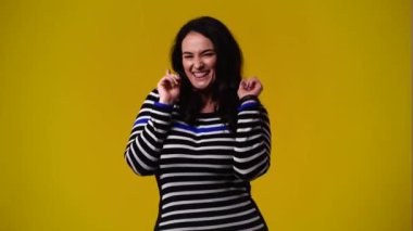 4k video of one woman showing thumbs up and smiling over yellow background. Concept of emotions.