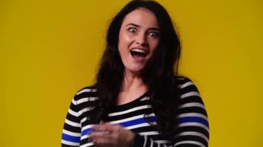 Sarı arka planda dönüp şaşıran bir kadının 4K videosu. Duyguların kavramı.