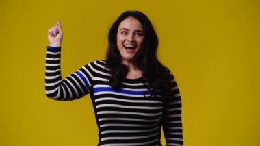 Bir kadının 4k videosu sarı arkaplanı işaret ediyor. Duyguların kavramı.