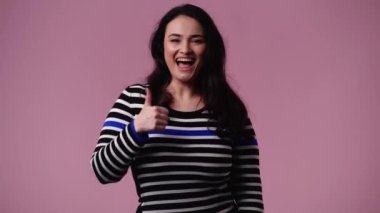 Pembe arka planda gülümseyen bir kadının 4K videosu. Duyguların kavramı.