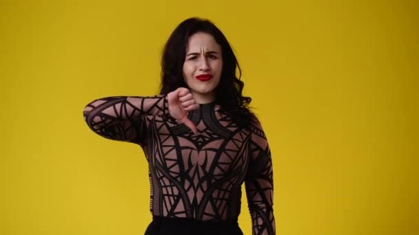 黄色の背景の上に親指を下に示す否定的な表情を持つ1人の女性の4Kビデオ 感情の概念 — ストック動画