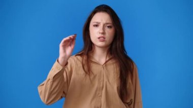 Mavi arka plandaki bir şeye negatif tepki veren bir kızın 4k yavaş çekim videosu. Duyguların kavramı.
