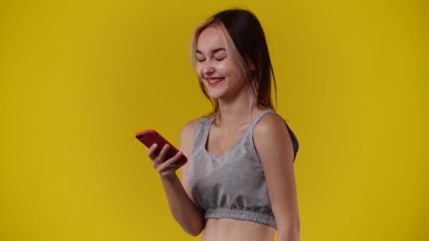 4K视频 一个女孩在黄色背景下对电话留言有情绪反应 情绪的概念 — 图库视频影像