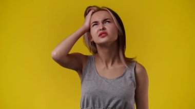 Bir kızın saçına dokunup sarı arka planda bir şey düşündüğü 4K video. Duyguların kavramı.