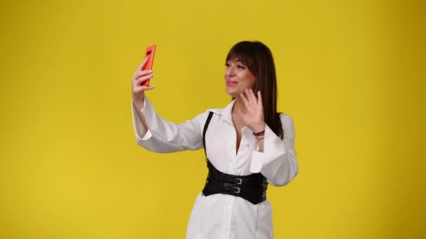 黄色の背景で彼女の携帯電話を使用して女性の4Kビデオ 感情の概念 — ストック動画