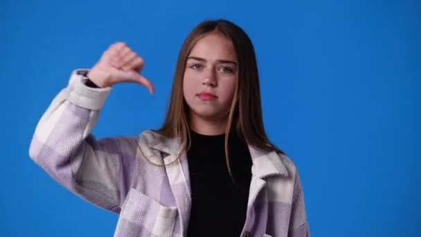 Vídeo Uma Menina Mostrando Polegar Para Baixo Fundo Azul Conceito — Vídeo de Stock