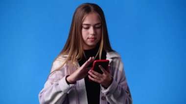 4K video 'da bir kız kamerayı işaret ediyor ve mavi arka planda başparmak gösteriyor. Duyguların kavramı.