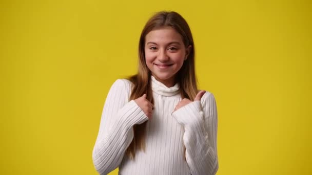 4Kビデオの女の子は黄色の背景に狡猾な顔の表情で彼女の顔に触れる 感情の概念 — ストック動画