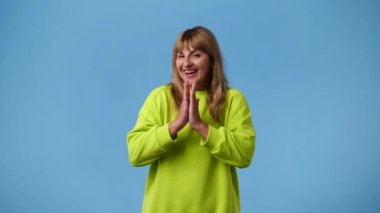 4k video of excited girl clapping in hands on blue background. Concept of emotions.