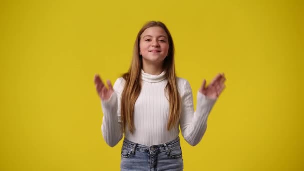 4Kビデオの女の子は黄色の背景に狡猾な顔の表情で彼女の顔に触れる 感情の概念 — ストック動画