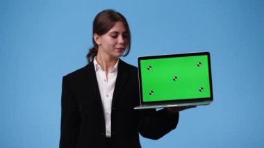 4k videoda bir kız krom anahtar dizüstü bilgisayar kullanıyor ve mavi arkaplanı onaylıyor. Duygu kavramı..