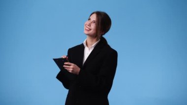 4k video of woman taking down some notes with a pen on blue background. Concept of emotions.
