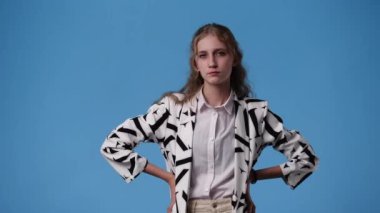 Mavi arka planda kurnaz yüz ifadesi olan bir kızın 4K videosu. Fikirleri olan kız kavramı.