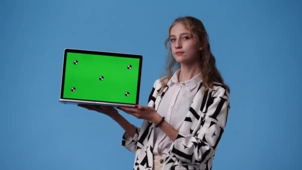 クロマキーノートパソコンを使用した1人の少女の4Kビデオと青の背景に親指を表示します 感情の概念 — ストック動画