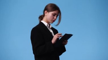 Elinde tablet tutan ve mavi arka planda baş parmağını gösteren bir kızın 4K videosu. Duyguların kavramı.