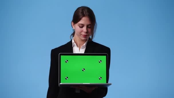 ノートパソコンを持って青い背景に親指を立てている女の子の4K動画 感情の概念 — ストック動画