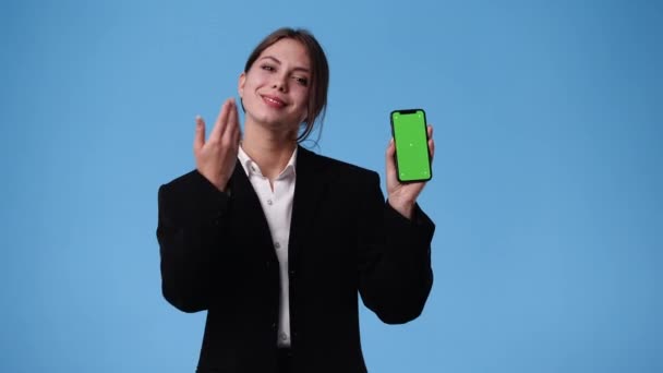 Vídeo Uma Garota Que Mostra Algo Telefone Sobre Fundo Azul — Vídeo de Stock