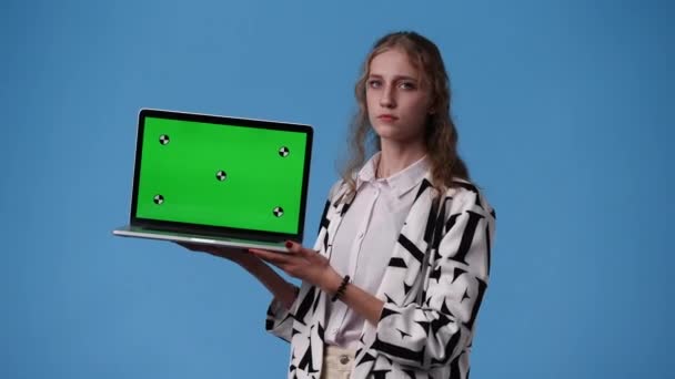 ノートパソコンを持って青い背景に親指を下に示す1人の女の子の4Kビデオ 感情の概念 — ストック動画