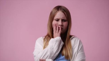 4k video of one girl with negative facial expression over pink background. Concept of emotions.