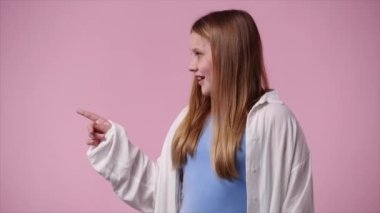 Sol tarafı işaret eden bir kızın 4K videosu ve pembe arka planda baş parmağını gösteriyor. Duyguların kavramı.