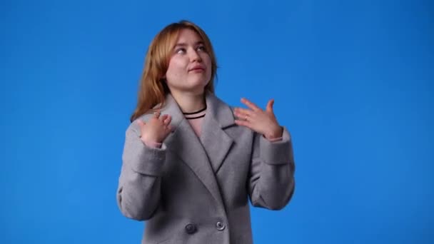青い背景の上にビデオをポーズしている1人の女の子の4Kビデオ 感情の概念 — ストック動画