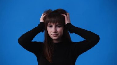 Mavi arka planda kendini kötü hisseden bir kızın 4K videosu. Duyguların kavramı.