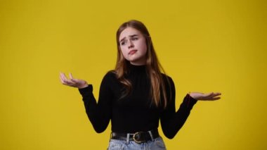 4k video of one girl pointing at left over yellow background. Concept of emotions.