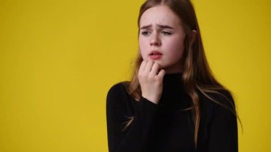 4k video of one girl with negative facial expression over yellow background. Concept of emotions.