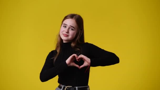 Video Jenter Som Lager Hjerteform Med Hendene Gul Ryggstøtte Kjærlighetsbegrepet – stockvideo