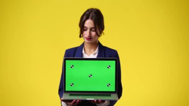 Krom anahtar dizüstü bilgisayar kullanan ve sarı arka planda gülümseyen bir kızın 4K videosu. Duygu kavramı..