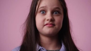 Pembe arka planda düşünceli yüz ifadesi olan bir kızın 4K videosu. Fikirleri olan kız kavramı.