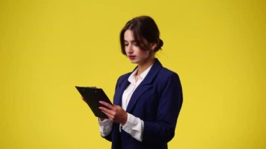 4k video of one girl thinking about something with note pad on yellow background. Concept of emotions.