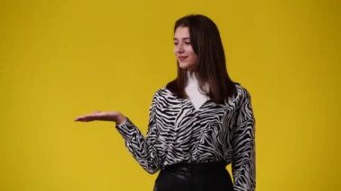 Sol tarafı işaret eden ve sarı arka planı gösteren bir kızın 4K videosu. Duygu kavramı.