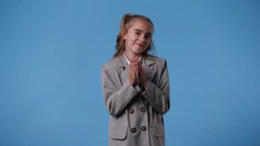 Mavi arka planda kurnaz yüz ifadesi olan bir kızın 4K videosu. Fikirleri olan kız kavramı.