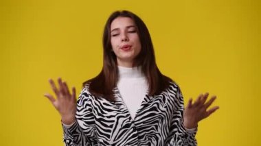 Sarı arka planda poz veren bir kızın 4K videosu. Duyguların kavramı.