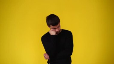 4k video of a man thinking about something over yellow background. Concept of emotions.